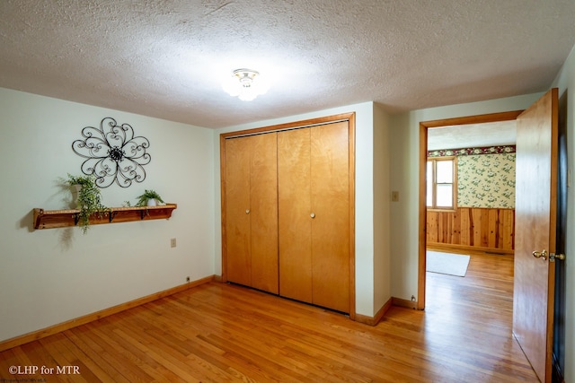 22 N Euclid Ave, Thomas, WV 26292 - unfurnished bedroom featuring light wood-style floors, a textured ceiling, baseboards, a closet, and a wainscoted wall