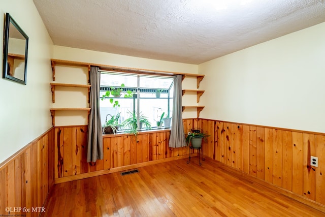 22 N Euclid Ave, Thomas, WV 26292 - empty room featuring a wainscoted wall, wood finished floors, wooden walls, and a textured ceiling