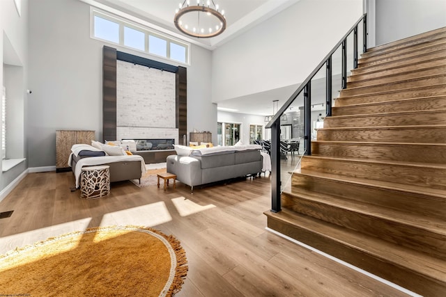 foyer with a towering ceiling, stairway, wood finished floors, a chandelier, and baseboards