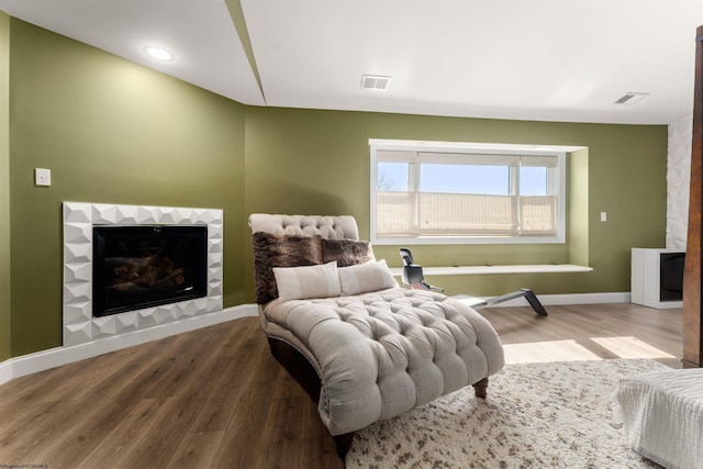 bedroom with wood finished floors, baseboards, and a fireplace