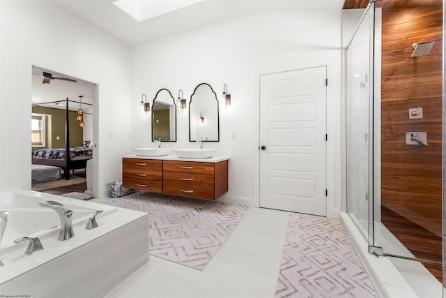 ensuite bathroom featuring a skylight, double vanity, a whirlpool tub, and a stall shower