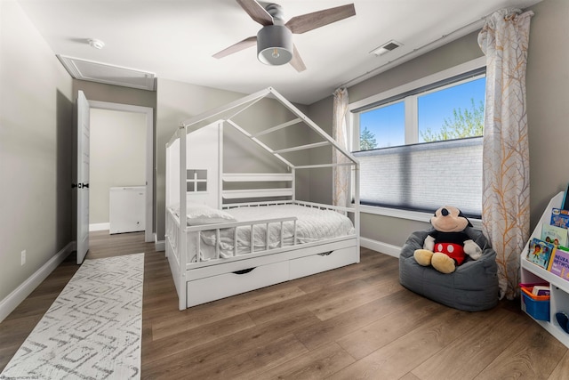 bedroom featuring attic access, wood finished floors, baseboards, ceiling fan, and fridge