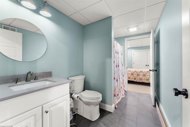 bathroom featuring a paneled ceiling, baseboards, toilet, vanity, and tile patterned floors