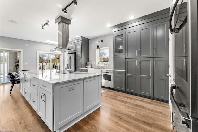 kitchen with plenty of natural light, stainless steel appliances, a center island, glass insert cabinets, and recessed lighting