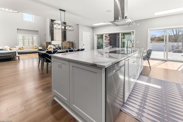 kitchen with island range hood, an island with sink, wood finished floors, and plenty of natural light