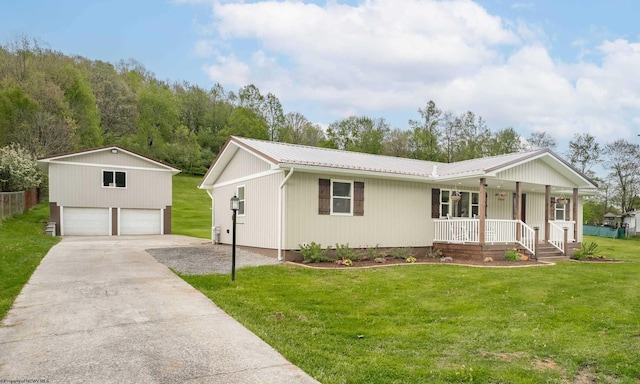 ranch-style house with a porch, a detached garage, a front lawn, metal roof, and an outbuilding
