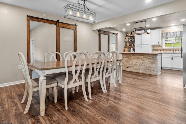 dining space with a barn door, dark wood finished floors, and recessed lighting