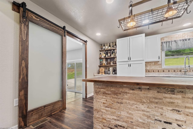 indoor dry bar featuring a barn door, backsplash, dark wood finished floors, recessed lighting, and baseboards