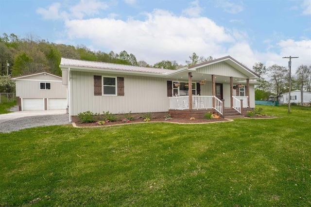 single story home featuring covered porch, an outbuilding, a front yard, a detached garage, and metal roof
