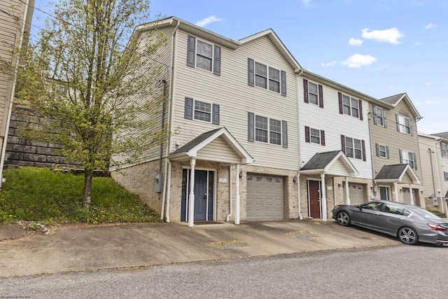 view of property featuring driveway, brick siding, and an attached garage