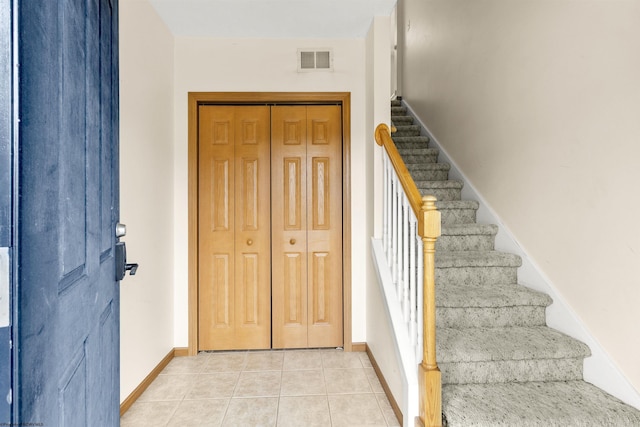 foyer entrance featuring stairway, baseboards, and light tile patterned floors