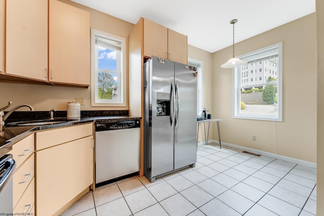 kitchen featuring stainless steel appliances, a sink, dark countertops, hanging light fixtures, and baseboards