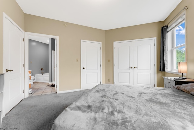 tiled bedroom with carpet flooring, a closet, baseboards, and connected bathroom