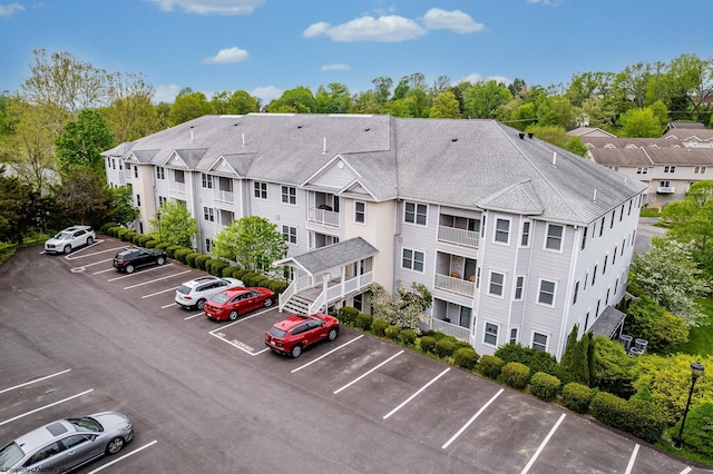 view of property with uncovered parking and view of wooded area