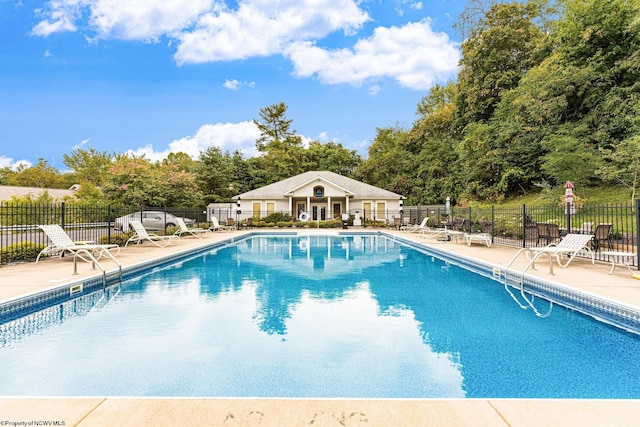 community pool featuring fence, a patio area, and view of scattered trees