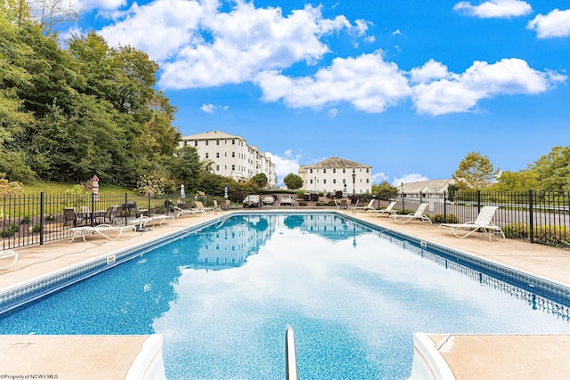 community pool with fence and a patio area