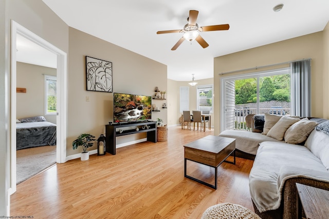 living room featuring a ceiling fan, light wood-style floors, and baseboards