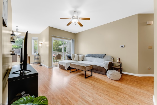 living area featuring light wood-style floors, a ceiling fan, and baseboards