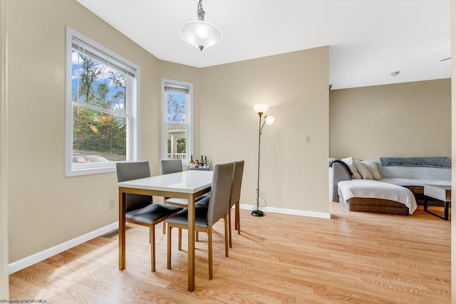 dining space with light wood-style flooring and baseboards