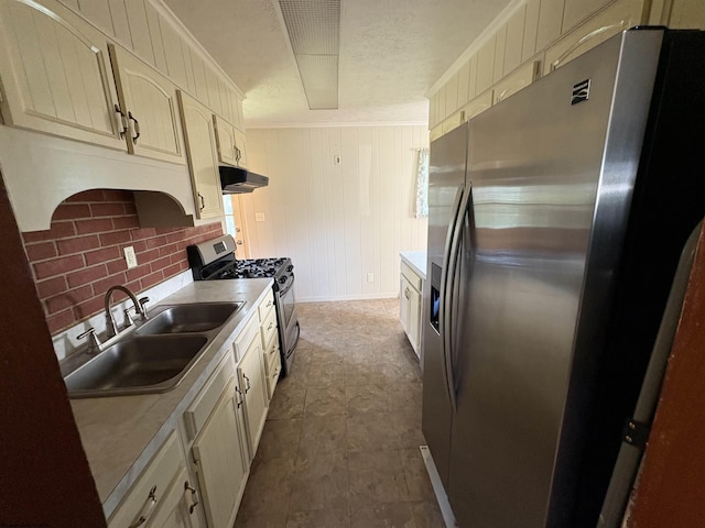 kitchen featuring appliances with stainless steel finishes, under cabinet range hood, a sink, light countertops, and crown molding