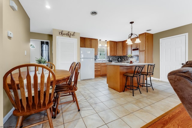 kitchen with freestanding refrigerator, decorative backsplash, light countertops, and light tile patterned floors