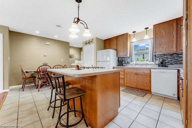 kitchen featuring white appliances, light tile patterned floors, backsplash, a center island, and light countertops