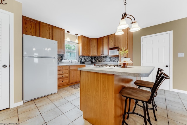 kitchen with white appliances, light tile patterned floors, light countertops, a kitchen island, and decorative backsplash
