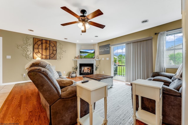 living area with ceiling fan, light wood-style flooring, a glass covered fireplace, baseboards, and recessed lighting