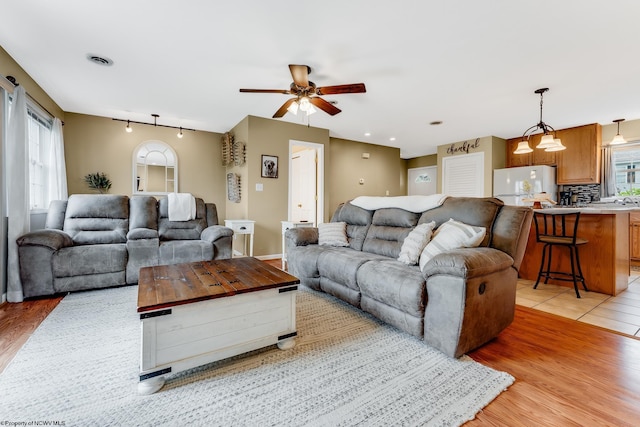 living room with a ceiling fan and light wood-type flooring