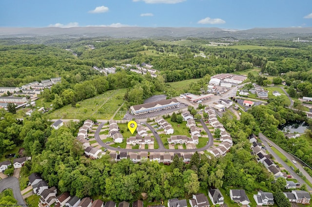aerial view of property and surrounding area with a heavily wooded area and nearby suburban area