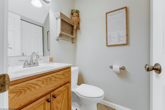 bathroom with toilet, vanity, and baseboards