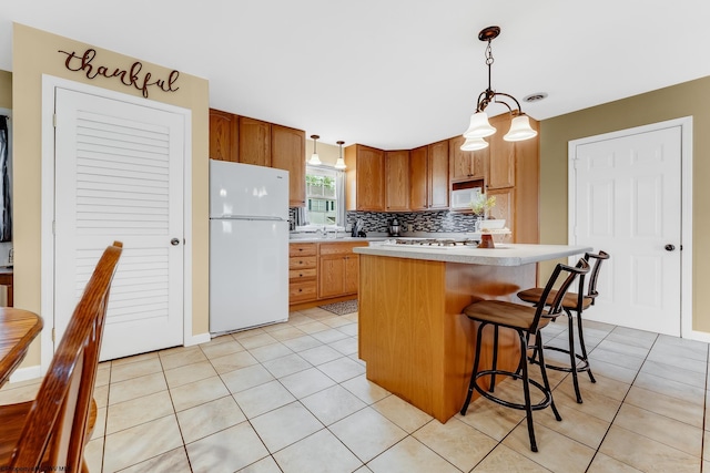 kitchen featuring white appliances, light countertops, light tile patterned floors, decorative backsplash, and decorative light fixtures