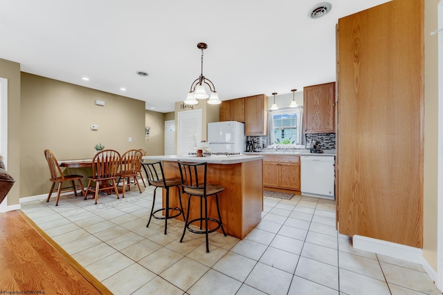 kitchen with white appliances, a center island, light tile patterned floors, light countertops, and decorative backsplash