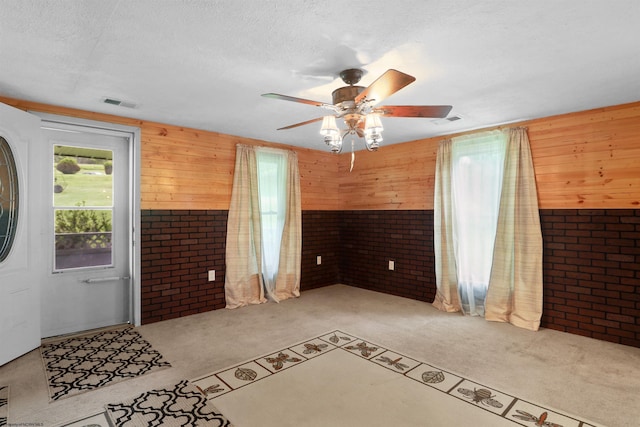 107 Orchard St, Masontown, WV 26542 - unfurnished living room featuring carpet floors, brick wall, wooden walls, a ceiling fan, and a textured ceiling