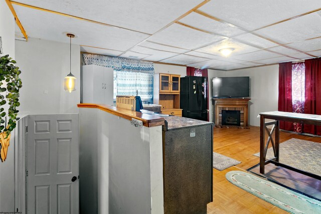107 Orchard St, Masontown, WV 26542 - kitchen with freestanding refrigerator, a peninsula, glass insert cabinets, a fireplace, and pendant lighting