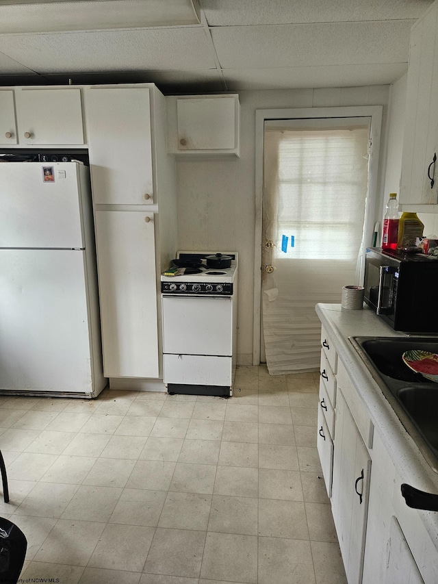 kitchen with white appliances, white cabinetry, light countertops, and a sink