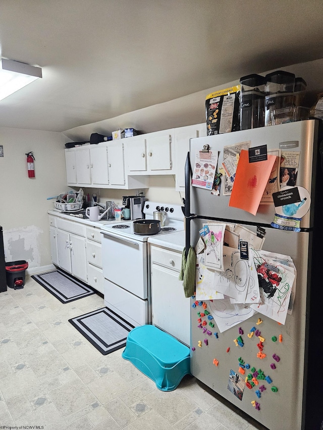 kitchen with freestanding refrigerator, electric range, light countertops, and white cabinets