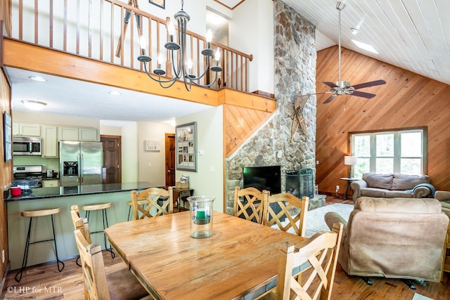 434 Cabin Mountain Rd, Davis, WV 26260 - dining area featuring high vaulted ceiling, a chandelier, wood walls, a fireplace, and light wood finished floors