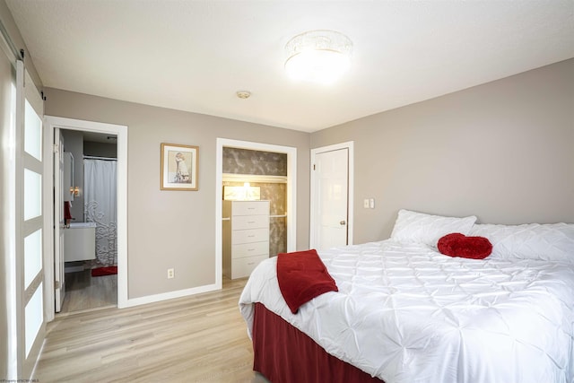 213 Forest Dr, Bridgeport, WV 26330 - bedroom with light wood-type flooring, baseboards, connected bathroom, and a barn door