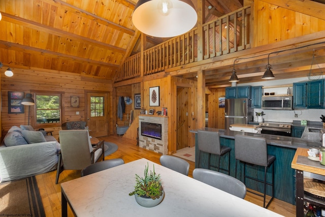 1 Ginger Ct, Terra Alta, WV 26764 - dining space featuring wood walls, light wood finished floors, a glass covered fireplace, high vaulted ceiling, and wood ceiling with exposed beams