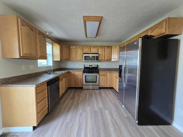 608 Ohio Ave, Nutter Fort, WV 26301 - kitchen featuring stainless steel appliances, a sink, light wood-style flooring, dark countertops, and a textured ceiling