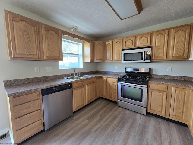 608 Ohio Ave, Nutter Fort, WV 26301 - kitchen featuring stainless steel appliances, a sink, light wood-style flooring, a textured ceiling, and dark countertops