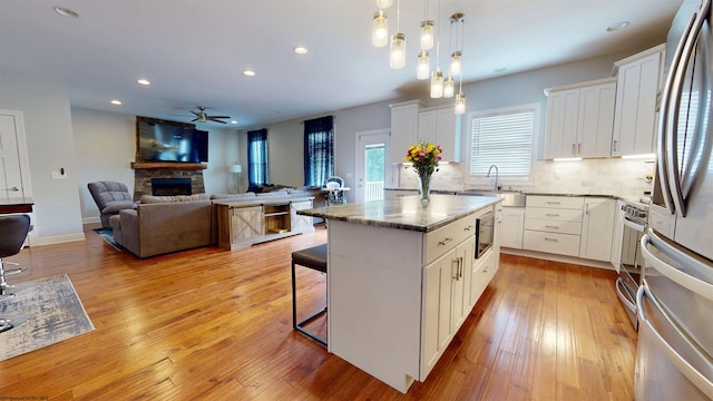 123 Sadie Ln, Morgantown, WV 26508 - kitchen featuring a stone fireplace, a breakfast bar area, ceiling fan, appliances with stainless steel finishes, and a kitchen island