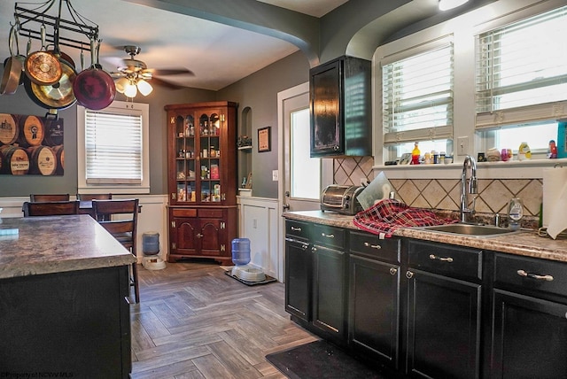 1917 Pleasant Valley Rd, Fairmont, WV 26554 - kitchen with dark cabinetry, a sink, arched walkways, a ceiling fan, and a wainscoted wall