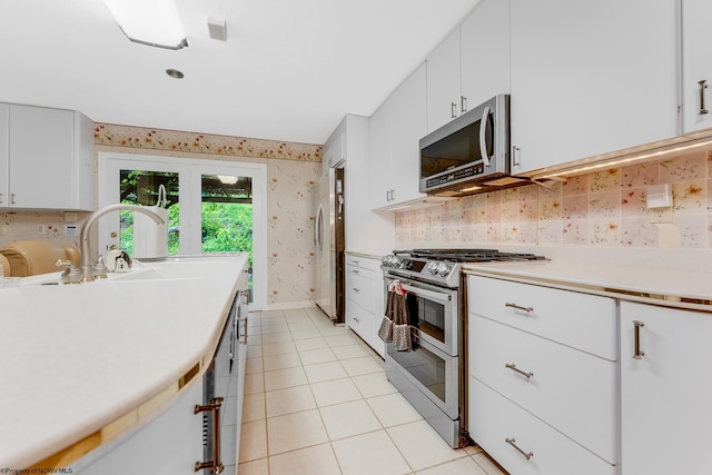 237 Highland Ave, Grafton, WV 26354 - kitchen featuring stainless steel appliances, wallpapered walls, light tile patterned floors, light countertops, and white cabinetry