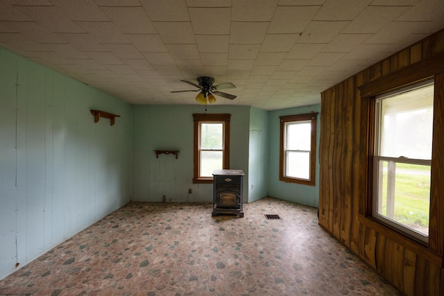 248 Casteel Rd, Terra Alta, WV 26764 - unfurnished living room featuring wood walls, a ceiling fan, and a wood stove