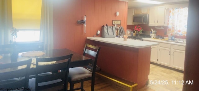 344 Tygart St, Fairmont, WV 26554 - kitchen with stainless steel microwave, a sink, white cabinets, light countertops, and a peninsula
