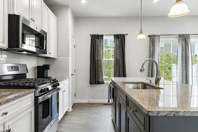 233 Stonehurst Dr, Morgantown, WV 26501 - kitchen with appliances with stainless steel finishes, a sink, decorative backsplash, light wood-style floors, and an island with sink