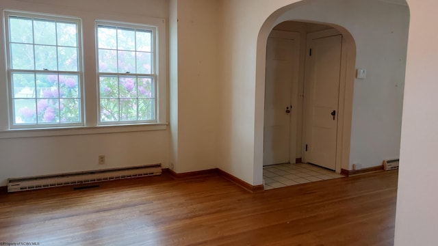 110 15th St, Elkins, WV 26241 - spare room with baseboard heating, arched walkways, light wood-type flooring, a baseboard heating unit, and baseboards