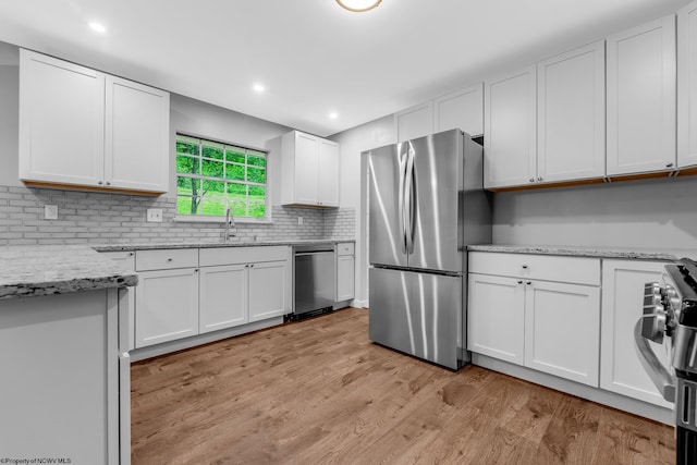 135 Celtic Dr, Clarksburg, WV 26301 - kitchen with appliances with stainless steel finishes, a sink, white cabinets, light wood finished floors, and tasteful backsplash
